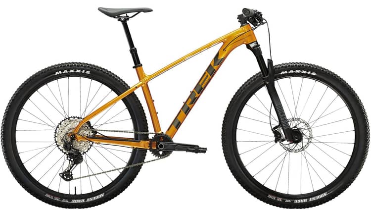 Orange Trek X-Caliber 9 mountain bike with RockShox fork and Maxxis tires, isolated on white background.