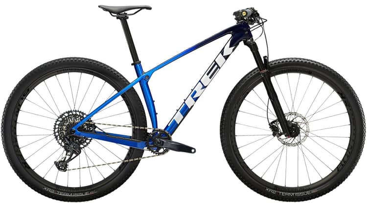 Blue Trek Procaliber 9.7 mountain bike with a carbon frame, large knobby tires, and a sophisticated gear system.