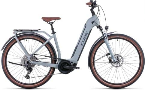 Cube Touring grey women's electric bike with tan saddle and grips, disc brakes, and rear carrier.