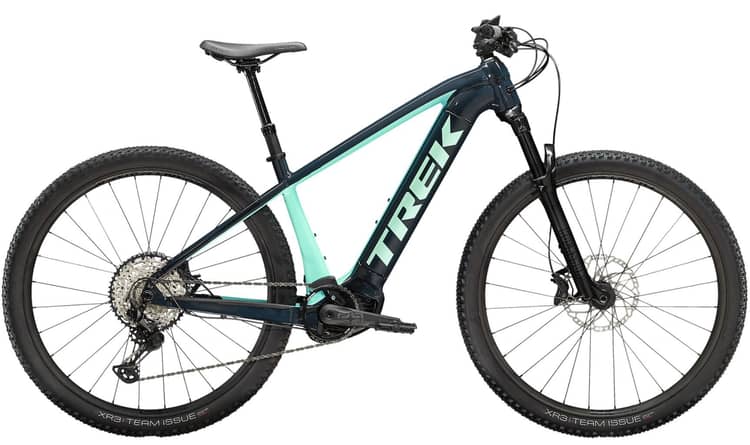 Trek mountain bike with teal and black frame, large tread tires, and gear system on white background.